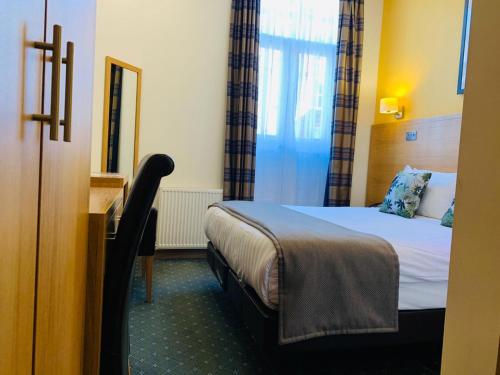 a hotel room with a bed and a mirror at Regency Hotel Parkside in London