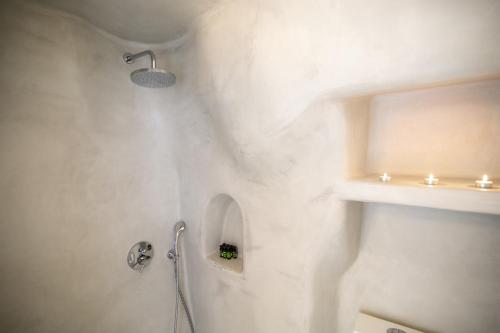 a white bathroom with a shower and a sink at Opsis Cave House in Oia