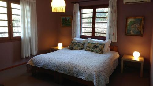 um quarto com uma cama com duas janelas e duas luzes em Gerakina beach cottage em Psakoudia