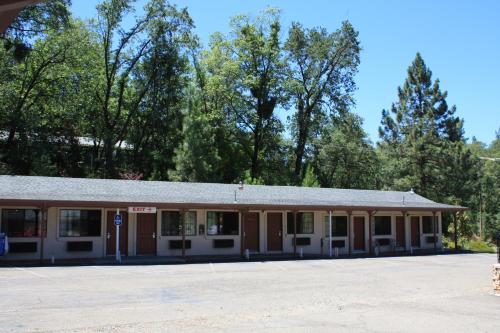 an old building in a parking lot with trees in the background at Mother Lode Motel in Placerville