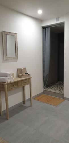 a bathroom with a shower and a table with a mirror at Hôtel Althea - Piscine et Sauna in Béziers