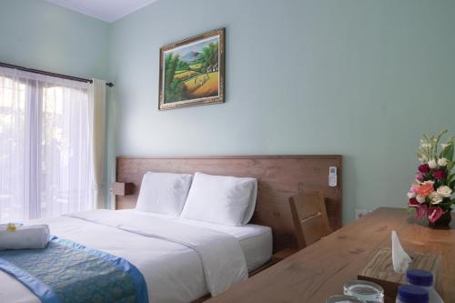 a bedroom with a bed and a table and a picture on the wall at Astana House in Ubud