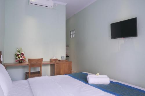 a bedroom with a bed and a desk with a television at Astana House in Ubud