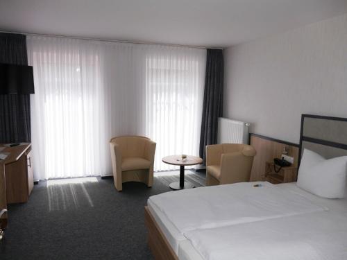 a hotel room with a bed and a table and chairs at Hotel Diekgerdes, in Cloppenburg