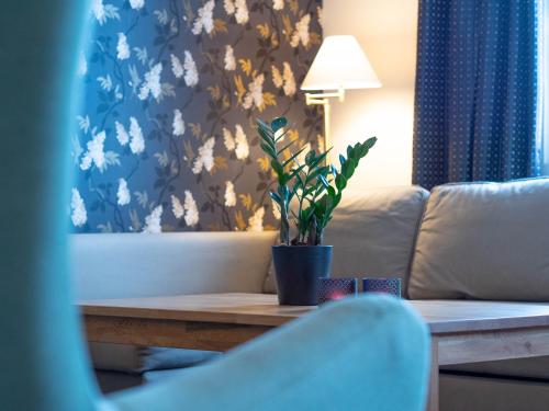 a living room with a couch and a table with a plant at Björkbackens Karaktärshotell in Vimmerby