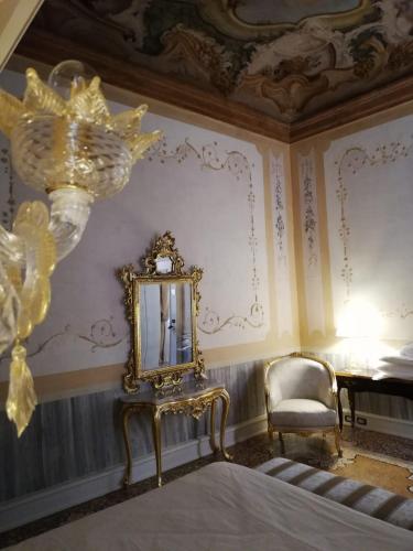 a gold mirror and a chair in a room at Ca' Bonfadini Historic Experience in Venice