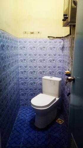 a bathroom with a toilet and a blue tiled wall at Nakula's Guest House in Banyuwangi