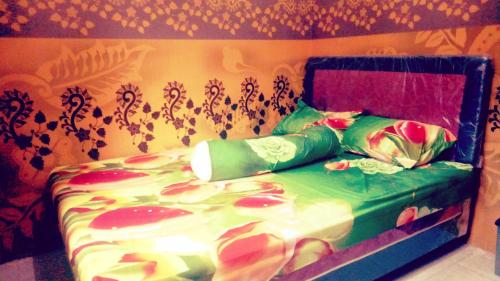 a bedroom with a bed with green sheets and flowers at Nakula's Guest House in Banyuwangi