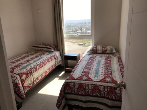 two beds in a room with a window at Departamento en Serena in Coquimbo