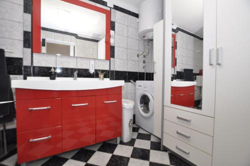 a red bathroom with a sink and a washing machine at Apartment Toya in Slatine
