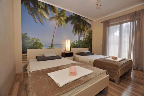 two beds in a room with a palm tree mural at Apartment Toya in Slatine