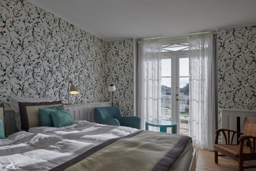 a bedroom with a bed and chairs and a window at Strandhotellet in Blokhus