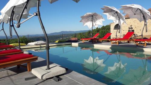 a swimming pool with chairs and umbrellas on a house at Le Pressoir De La Deveze in Vernon