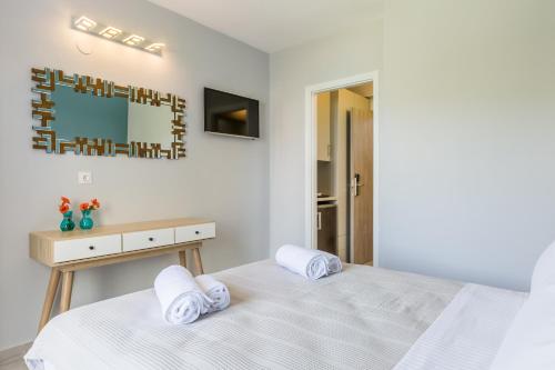 a white bedroom with a bed and a mirror at Olia Green Residence in Skopelos Town