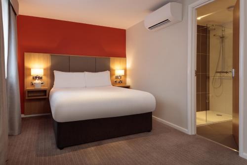 a bedroom with a large bed and a shower at Oxford Witney Hotel in Witney