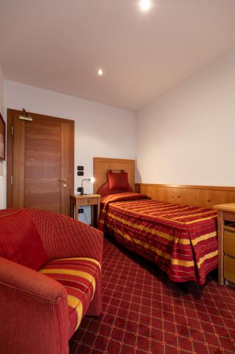 a hotel room with two beds and a couch at Hotel Isolabella Wellness in Fiera di Primiero