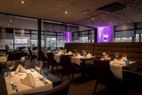 デルデンにあるHotel Wapen van Deldenの白いテーブルと椅子、紫色の照明が備わるレストラン