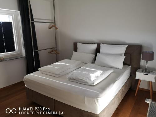 een bed met witte lakens en kussens in een kamer bij Luxuriöse Ferienwohnung im Herzen des Sauerlandes in Meschede