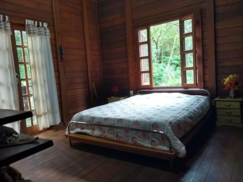 a bedroom with a bed in a room with windows at Chalé Cores da Mata in Brumadinho