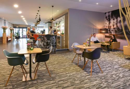 a restaurant with tables and chairs and people sitting at tables at ibis Kortrijk Centrum in Kortrijk