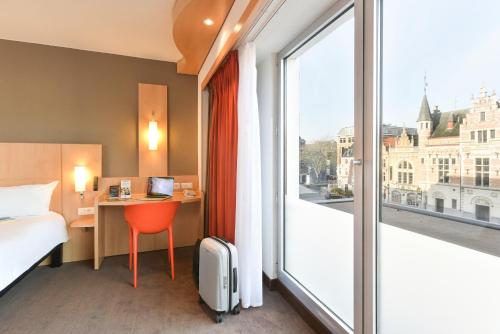 a hotel room with a bed and a desk and a window at ibis Kortrijk Centrum in Kortrijk