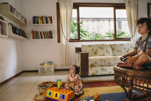 a little girl sitting in a living room with a child at Pousada Porto Mare in Maresias