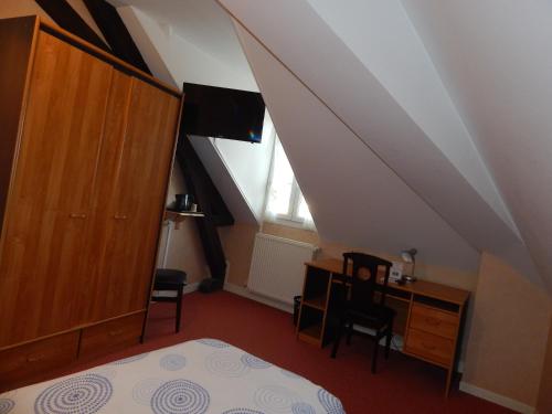 a bedroom with a bed and a desk and a window at Le Lion D'or in Ouroux en Morvan