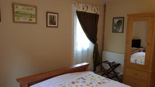 a bedroom with a bed and a mirror and a window at The Old Cottage in Arduaine