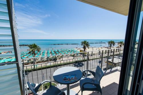 balcón con mesa y sillas y playa en Hotel Sole, en Montesilvano