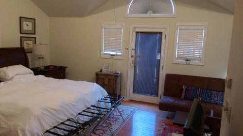 a bedroom with a bed and a couch and windows at Spacious master bedroom and bath in Wellesley