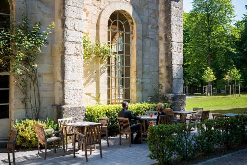 two people sitting at tables outside a building at Abbaye de Royaumont in Viarmes