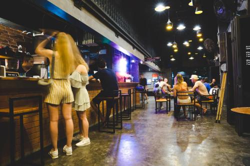 two women standing at a bar in a pub at BED STATION Hostel Khaosan in Bangkok