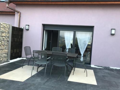 une table et des chaises sur une terrasse avec une fenêtre dans l'établissement Gîte aux deux Hameaux, à Saint-Pierre-Bois