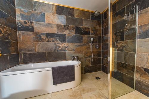 La salle de bains est pourvue d'une baignoire et de murs carrelés. dans l'établissement Lorien Lodge, à Breakish