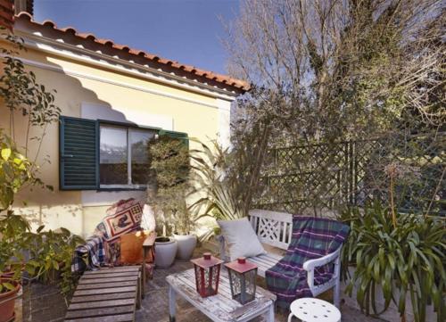 a patio with two chairs and a table in front of a house at At Home Sintra in Sintra