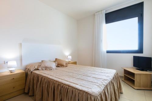 1 dormitorio con cama, ventana y TV en MILLENIUM 1 2-2, en Roses