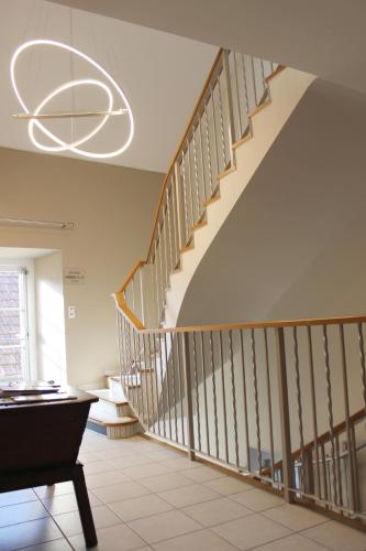 a hallway with a staircase with a chandelier at Hotel le Vauxois in Vaux-sous-Aubigny