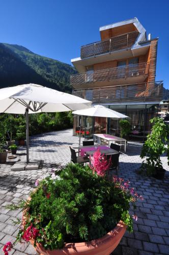 ザンクト・アントン・アム・アールベルクにあるSkihotel Galzig B&Bの建物の前にテーブルと傘と花が並ぶパティオ