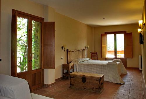 a bedroom with a bed and a table and windows at Hostal Les Roquetes in Queralbs