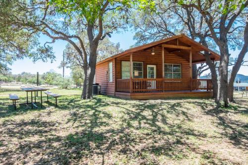 a log cabin with a picnic table and trees at River Bluff Cabins in Rio Frio
