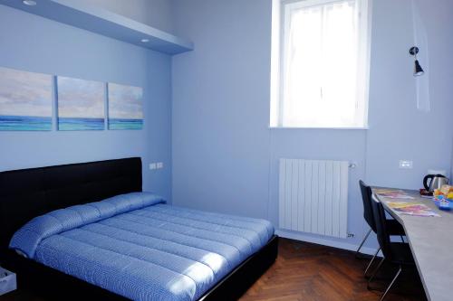 - une chambre bleue avec un lit et un bureau dans l'établissement MONOLOCALE VICINO MILANO 2, à Lodi