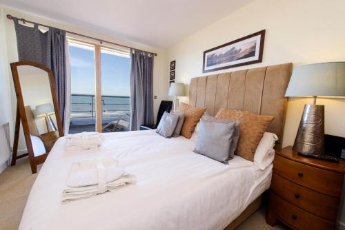 a bedroom with a large white bed with a view of the ocean at The Sands in Scarborough