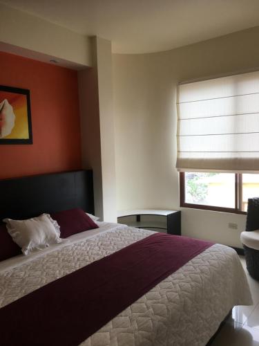 a bedroom with a large bed and a window at Hotel San Vicente Galapagos in Puerto Villamil