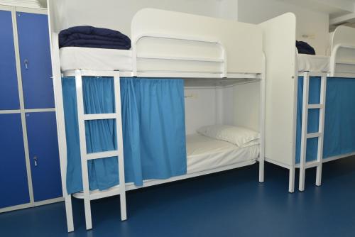 a room with three bunk beds with blue walls at Hostel Albergue Baionamar in Baiona