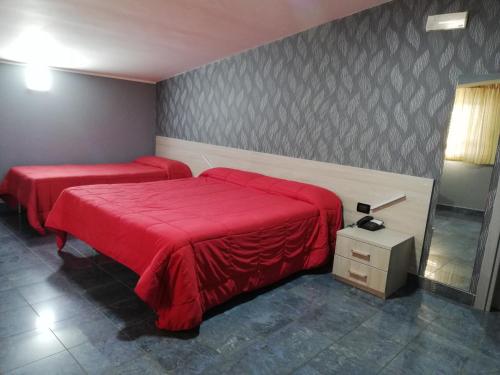 a bedroom with two beds with red sheets at Motel Kratos in Bisignano
