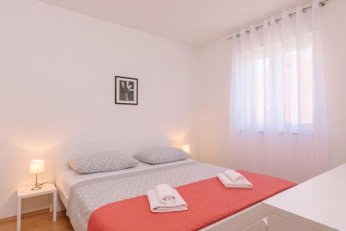 ein weißes Schlafzimmer mit einem Bett mit zwei Handtüchern darauf in der Unterkunft Apartman Niko in Kaštela