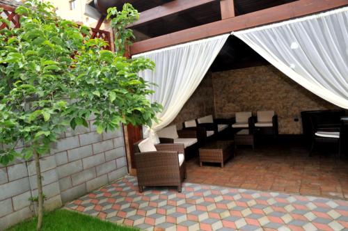 a patio with chairs and tables and a white curtain at Pensiunea Normandia in Timişoara