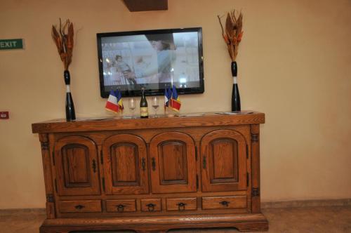 a tv on top of a wooden cabinet with flags on it at Pensiunea Normandia in Timişoara