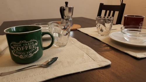a table with a green coffee cup and glasses on it at AT HOME IN CREMONA in Cremona