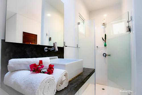 uma casa de banho com um lavatório branco e toalhas em Jardim Secreto em Morro de São Paulo